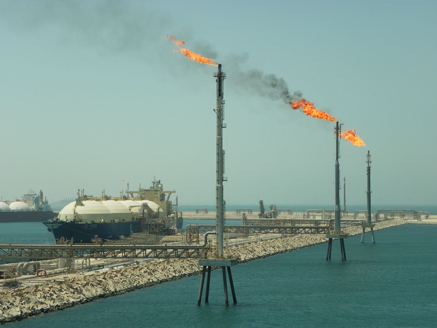 LNG carrier loading at Ras Laffan LNG Terminal, Qatar, with flare stacks in the foreground